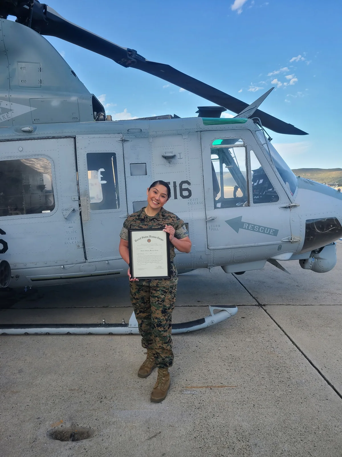 Monique Emerson in Marine Corps uniform beside a military helicopter